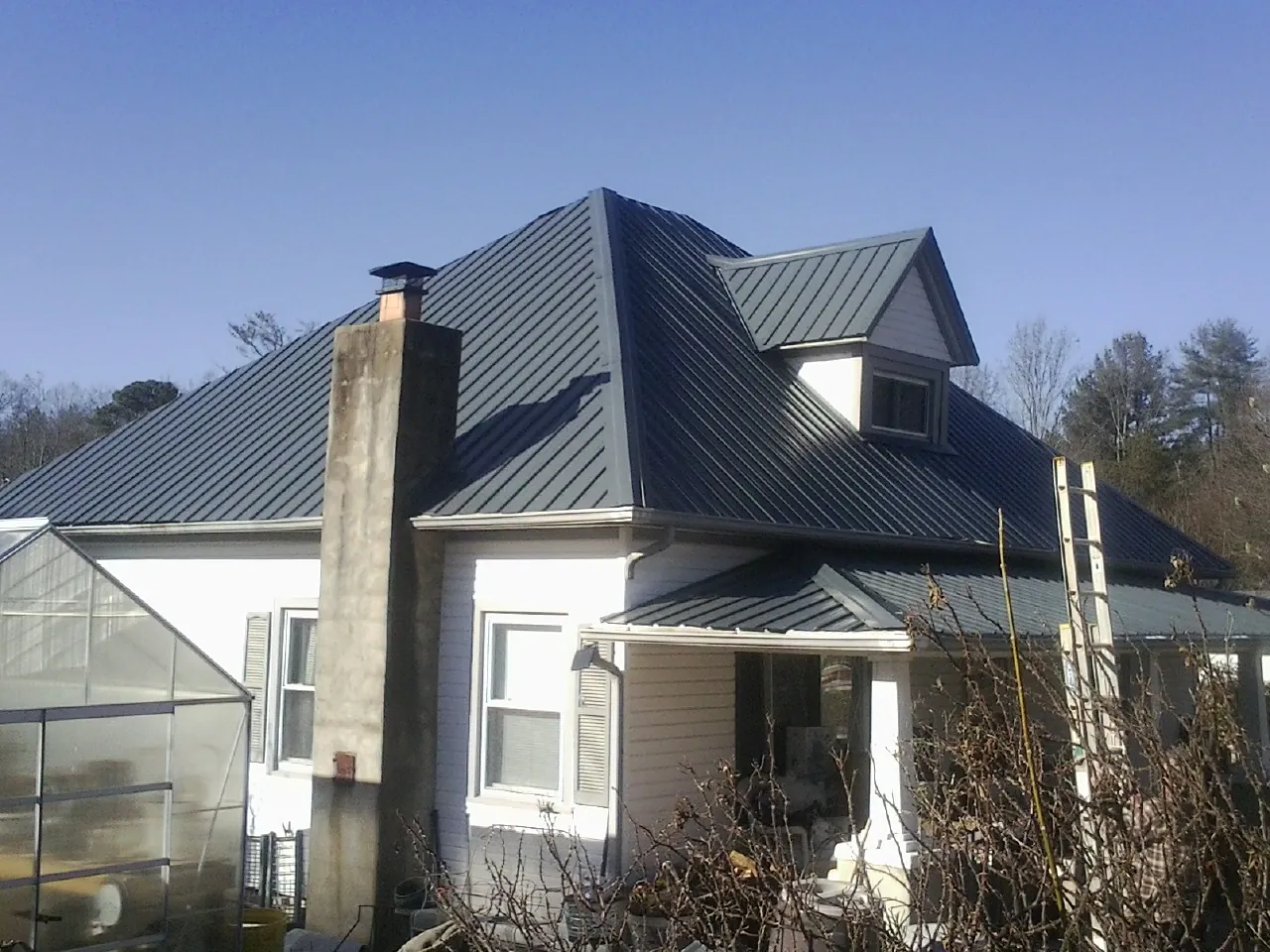 Dark blue standing seam metal roof on a white farmhouse with dormer — Slate & Tile Roof Repair by Roofing Brothers in Columbia City