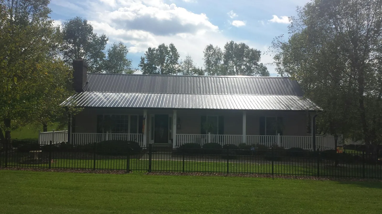 Gray metal roof on a brick ranch with a full width front porch — Gutter Guard Installation work by our crew in Columbia City