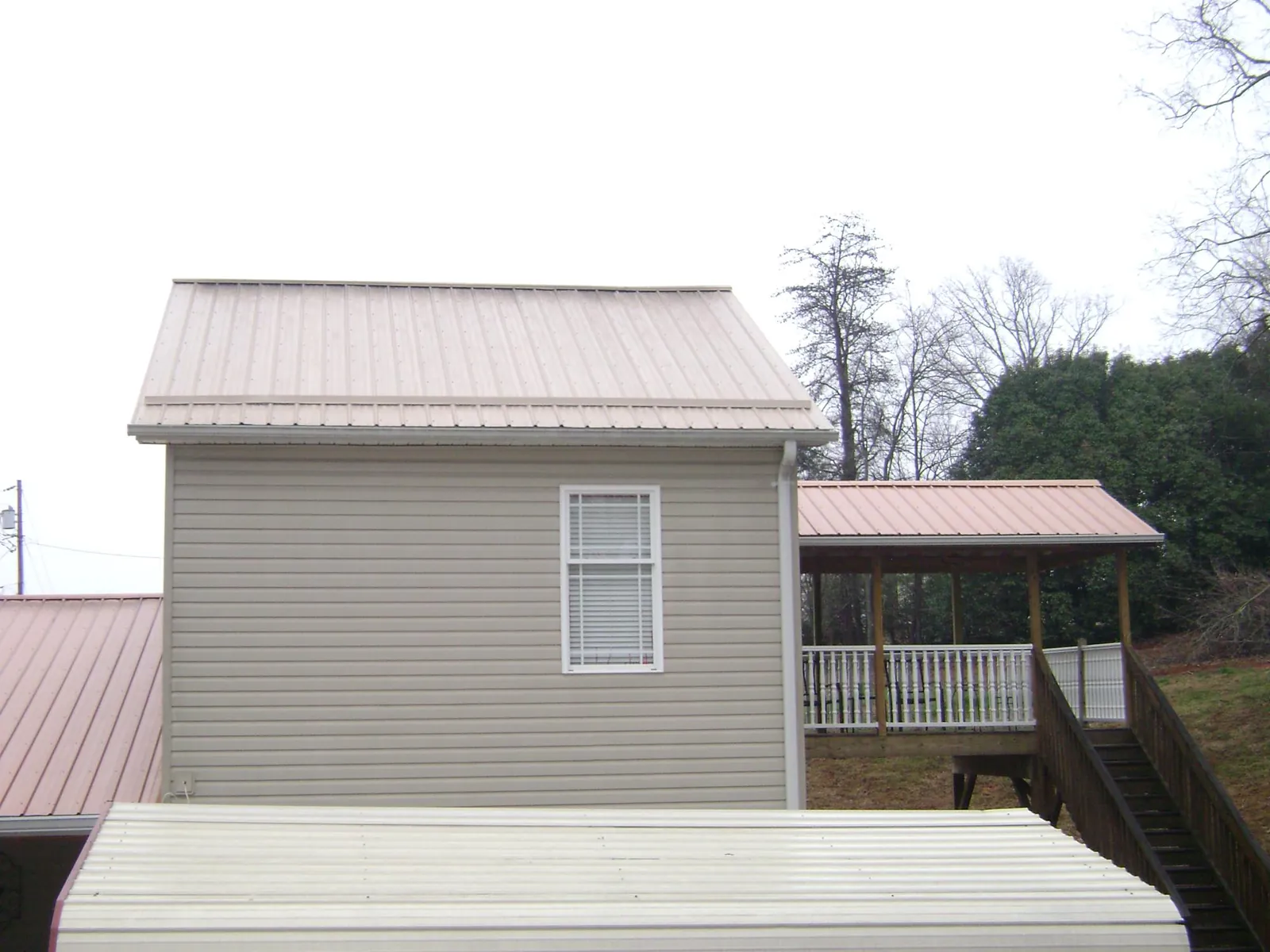 Tan metal roofs on a two story addition and attached porch, from a Roof Replacement job in Columbia City